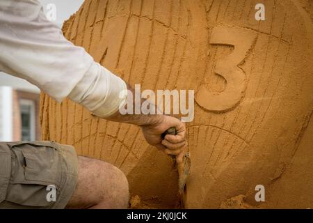 Sandskulpturenbauer, der an einer Sandskulptur arbeitet Stockfoto