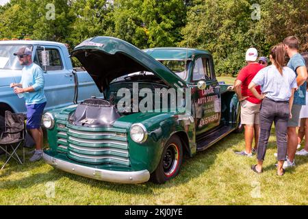 Auf einer Autoshow in Fort Wayne, Indiana, USA, versammeln sich die Besucher in einem klassischen grünen Chevrolet-Pick-up-Truck mit offener Motorhaube. Stockfoto