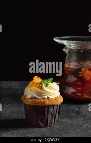 Cupcakes mit Käsesahne, dekoriert mit süßen Beeren auf dunklem Hintergrund Stockfoto