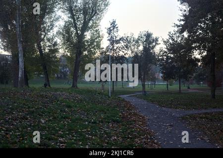 Wanderwege in einem Park neben einem See bei Sonnenuntergang im Herbst Stockfoto