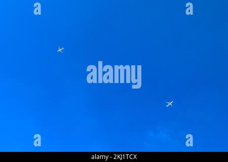 Zwei Passagierflugzeuge, die fliegen, isoliert am blauen Himmel. Blick von unten. Stockfoto