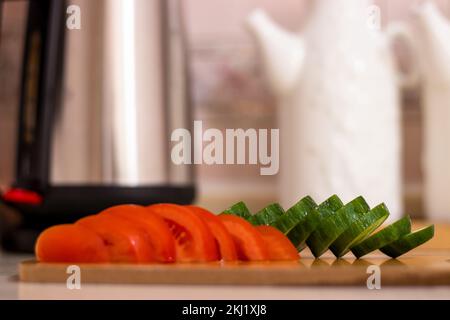 Frisch geschnittene Tomate und geschnittenes ​​cucumber-Küchengeschirr auf weißem Hintergrund; Öler und KetilSelektive Fokussierung Stockfoto