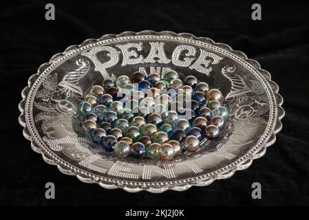 Farbenfrohe Marmor auf einem „Peace & Plenty“-Teller aus Glas. Diese sehen solide und weniger durchscheinend aus ... Bis sie im Licht gehalten werden. Stockfoto