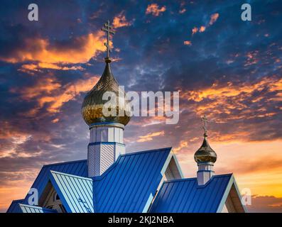 Ein Teilblick auf die orthodoxe Kirche unter dem dramatischen dunklen bewölkten Himmel bei Sonnenuntergang Stockfoto