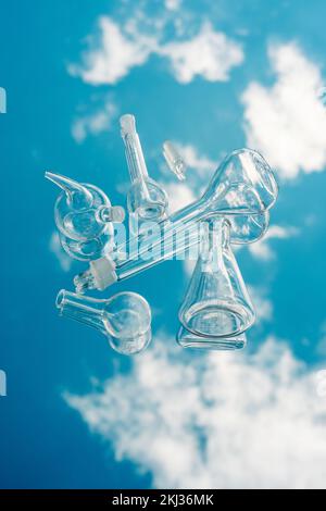 Verschiedene Laborglaswaren auf einem spiegelnden Hintergrund mit Himmelsreflexion. Wissenschaftliche Laborforschung und -Entwicklung Labor- und Entwicklungskonzept Stockfoto