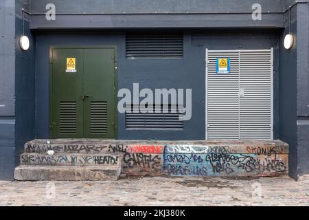 Eine blaue Tür in einer Stadtstraße in Shoreditch, London, Großbritannien, E1 mit Graffiti-Stufen. Stockfoto