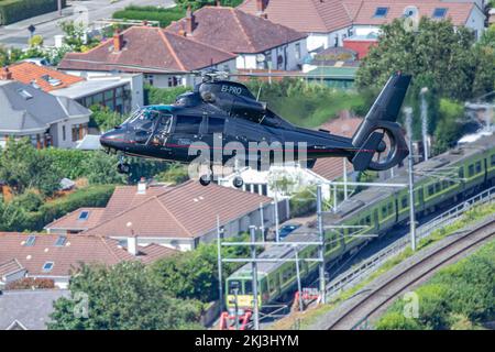 Ein schwarzer Eurocopter AS365 Dauphin fliegt über die Gebäude und einen Bahnhof während der Bray Air Display Flugshow Stockfoto