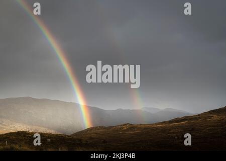 Ein nasses, herbstliches HDR-Bild eines doppelten Regenbogens über der Sutherland-Landschaft bei Unapool in den schottischen Highlands. 26. Oktober 2022 Stockfoto