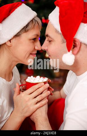 Ein junges Paar trinkt Kaffee im Weihnachtsbaum. Ein Paar entspannt sich Stockfoto