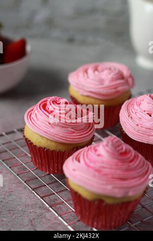 Nahaufnahme von Vanille-Muffins, die mit rosa Buttercreme-Zuckerguss auf der Oberseite verziert sind Stockfoto