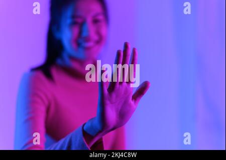 Ein flaches Fokusbild einer südostasiatischen weiblichen Hand im farbenfrohen Hintergrund Stockfoto