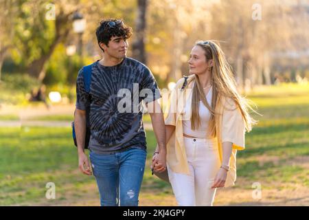 Ein junges heterosexuelles Paar, das in einem Park spaziert und sich anschaut Stockfoto