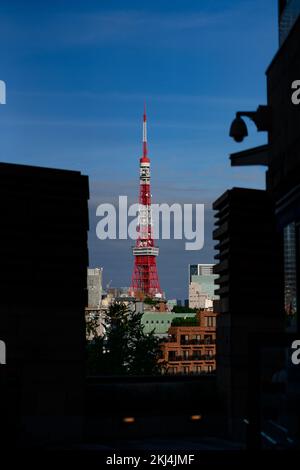 Ein roter und weißer Telekommunikationsturm in der modernen Stadt vor einem blauen Himmel Stockfoto