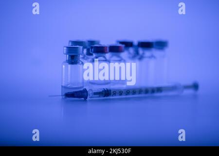 Impfstoffflasche, Spritze mit Grippeschutznadel, medizinisches Impfkonzept, subkutane Injektion auf blauem Hintergrund. Speicherplatz kopieren. Testimmunisierung und Stockfoto