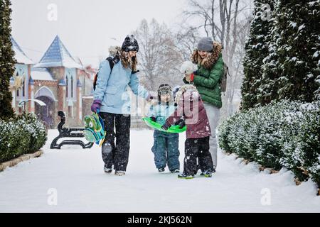 Winteraktivitäten im Freien für Familie und Freunde. Fröhliche Familie, Freunde, zwei Frauen, zwei Jungen und Hunde, Mütter und Söhne, die spazieren gehen und Spaß im Freien haben Stockfoto