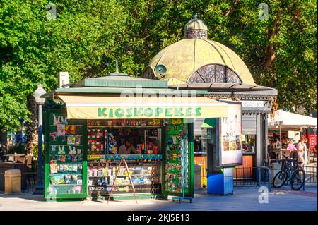 Alicante, Spanien - 12. September 2022: Ein kleiner Kiosk mit dem Schild „Kioskopekes“ in einem Park. Die Kabine ist neben einem Gebäude mit einem kuppelförmigen Dach, an Stockfoto