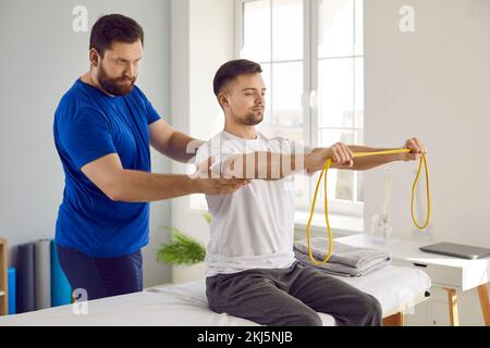 Physiotherapeut-Patient, der körperliche Rehabilitationsübungen mit Resistenzband macht Stockfoto