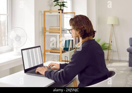 Geschäftsmann, der sich auf die Arbeit an einem Projekt konzentriert und mit einem digitalen Programm auf einem Notebook arbeitet. Stockfoto