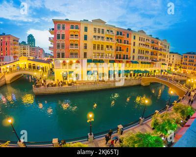 Weitwinkelblick auf zwei venezianische Brücken auf Kanälen mit malerischem und luxuriösem Wahrzeichen von Doha am Abend beleuchtet. Panorama von Venedig in Stockfoto