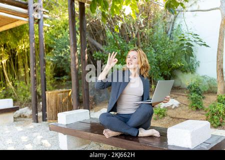 Eine schöne Freiberuflerin arbeitet im Park mit einem Computer. Stockfoto