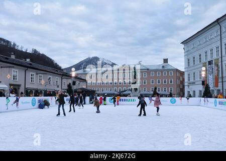 Salzburg, Österreich - 30. November 2019: Eislaufbahn in der Altstadt von Salzburg, Österreich mit Gebäuden und einem Berg im Hintergrund. Stockfoto