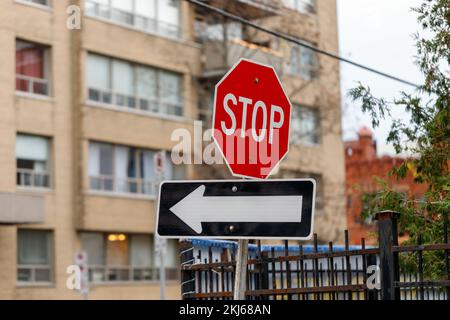 Rotes Stoppschild und Pfeil zeigen die Verkehrsrichtung auf der Straße an Stockfoto