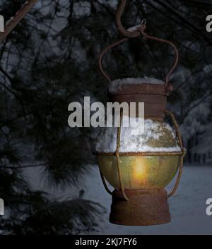 Alte schneebedeckte Laterne, die an Heiligabend an einem Baum hängt Stockfoto