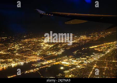 Fantastische Aussicht auf die Nachtstadt aus der Vogelperspektive. Die Stadt ist mit hellen Lichtern beleuchtet. Aufnahmen aus dem Fenster eines Flugzeugs, das in der fliegt Stockfoto