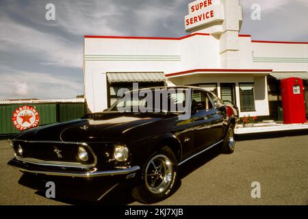Vintage-Foto eines Ford Mustang Fastback aus dem Jahr 1969 an einer Texaco-Tankstelle Stockfoto