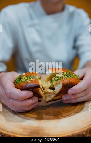 Eine vertikale Aufnahme eines Mannes, der einen veganen Burger isst Stockfoto