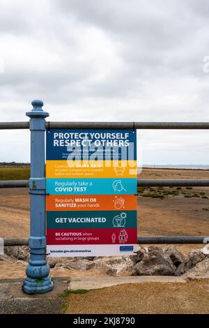 Covid-Sicherheitshinweis an Geländern an der Küste angebracht Stockfoto