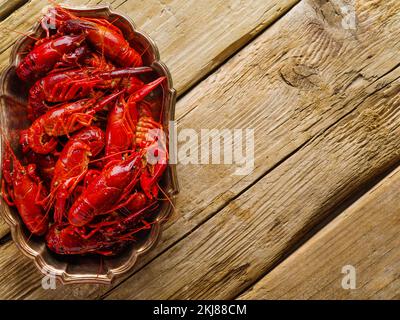 Leckere frisch zubereitete Flusskrebse auf einer Platte auf einem einfachen Holztisch. Nahaufnahme. Ansicht aus niedrigem Winkel. Zubereitung gesunder Meeresfrüchte-Gerichte. Rezepte, Kochen Stockfoto