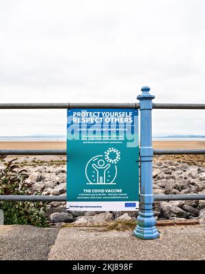 Covid-Sicherheitshinweis an Geländern an der Küste angebracht Stockfoto