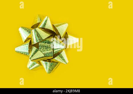 Frohes neues Jahr. Weihnachtsbanner Frohe Weihnachten. Glitzerndes Weihnachtsgeschenk mit Goldschleife auf gelbem Hintergrund. Stockfoto