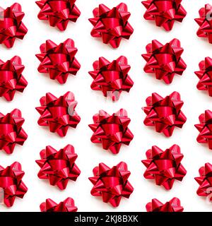 Festliche rote Schleifen auf weißem Hintergrund. Nahtloses Muster für Feiertage. Weihnachtskonzept. Stockfoto