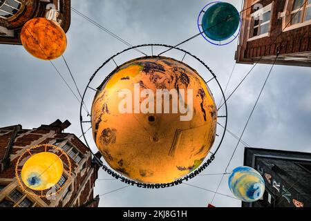 London, Großbritannien. 24.. November 2022. Ein riesiger Planet Erde und kleinere Planeten hängen hoch über der Straße. Einkaufslustige können bei nassem Wetter durch die Weihnachtslichter in der berühmten Carnaby Street von Soho schlendern und sie genießen. Die diesjährige Installation heißt „Carnaby Celebrations“ und feiert 25 Jahre der Weihnachtslichter der Carnaby Street. Kredit: Imageplotter/Alamy Live News Stockfoto