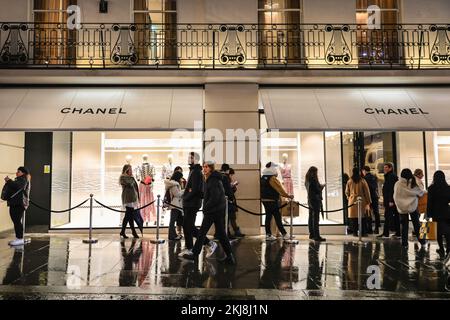 London, Großbritannien. 24.. November 2022. Lange Schlangen von Käufern warten geduldig vor dem Chanel Store. Menschen in der Bond Street, Mayfair's berühmter Einkaufsstraße, und entlang Piccadilly stöbern durch die Schaufenster und bewundern die vielen bunten Ausstellungen und aufwändigen Weihnachtsdekorationen in den Luxusgeschäften von Mayfair. Kredit: Imageplotter/Alamy Live News Stockfoto