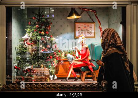 London, Großbritannien. 24.. November 2022. Einkaufslustige gehen vorbei und schauen sich hübsche dekorative Szenen in den Fenstern des Kaufhauses Fortnum & Mason an. Menschen in der Bond Street, Mayfair's berühmter Einkaufsstraße, und entlang Piccadilly stöbern durch die Schaufenster und bewundern die vielen bunten Ausstellungen und aufwändigen Weihnachtsdekorationen in den Luxusgeschäften von Mayfair. Kredit: Imageplotter/Alamy Live News Stockfoto