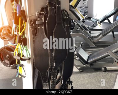 Sportliche Kraftgürtel im Fitnessraum, auf dem Hintergrund verschiedener Trainingsgeräte Stockfoto