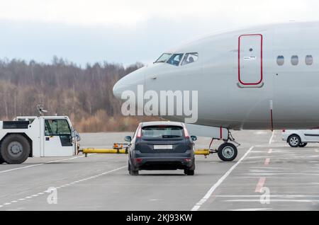 Schlepperflugzeug zurückschieben. Flugplatzservice im Auto wartet darauf, das Flugzeug an der Kreuzung zu verpassen Stockfoto