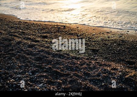 Steine und Blick auf den schwarzen Strand von Kamari in Santorin Stockfoto