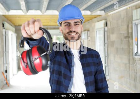 Junger Arbeiter mit Kopfhörer mit Geräuschminimierung in Weiß Stockfoto