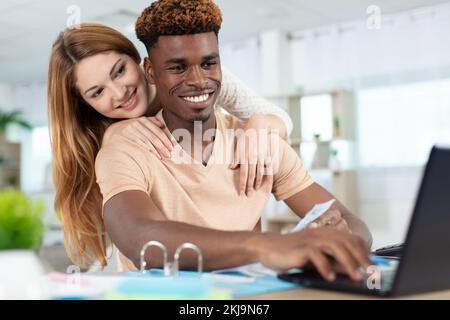 Lächelndes Paar, das den PC-Laptop überprüft Stockfoto
