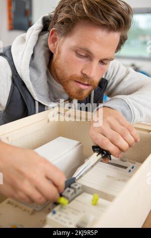 Elektriker, der Geräte in den Sicherungskasten verschraubt Stockfoto