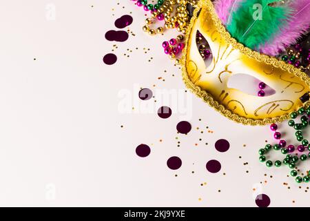 Zusammensetzung von farbigen mardi Gras-Perlen und Karnevalsmasken auf weißem Hintergrund mit Kopierraum Stockfoto