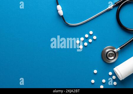 Zusammensetzung des Stethoskops mit Pillen auf blauem Hintergrund mit Kopierraum Stockfoto