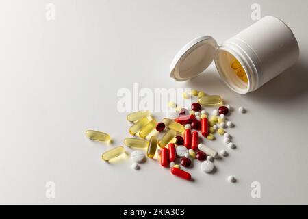 Zusammensetzung der Tablettenbox, die eine Vielzahl von Pillen und Kapseln auf weißem Hintergrund mit Kopierraum verschüttet Stockfoto