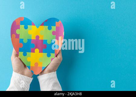 Zusammenstellung von Händen, die Puzzleherzen auf blauem Hintergrund halten, mit Kopierraum Stockfoto