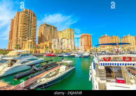 Doha, Katar - 18. Februar 2019: Marina corniche Promenade in Porto Arabia an der Pearl-Qatar, Doha, mit Wohntürmen und Luxusbooten und Stockfoto