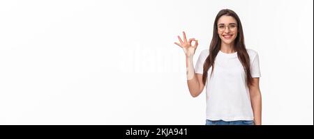 Taille-up-Porträt von optimistischen, lächelnd glücklich junge hübsche Frau in einer Brille, zeigt okay Zeichen, zustimmen oder empfehlen etwas, geben positive Bewertung Stockfoto